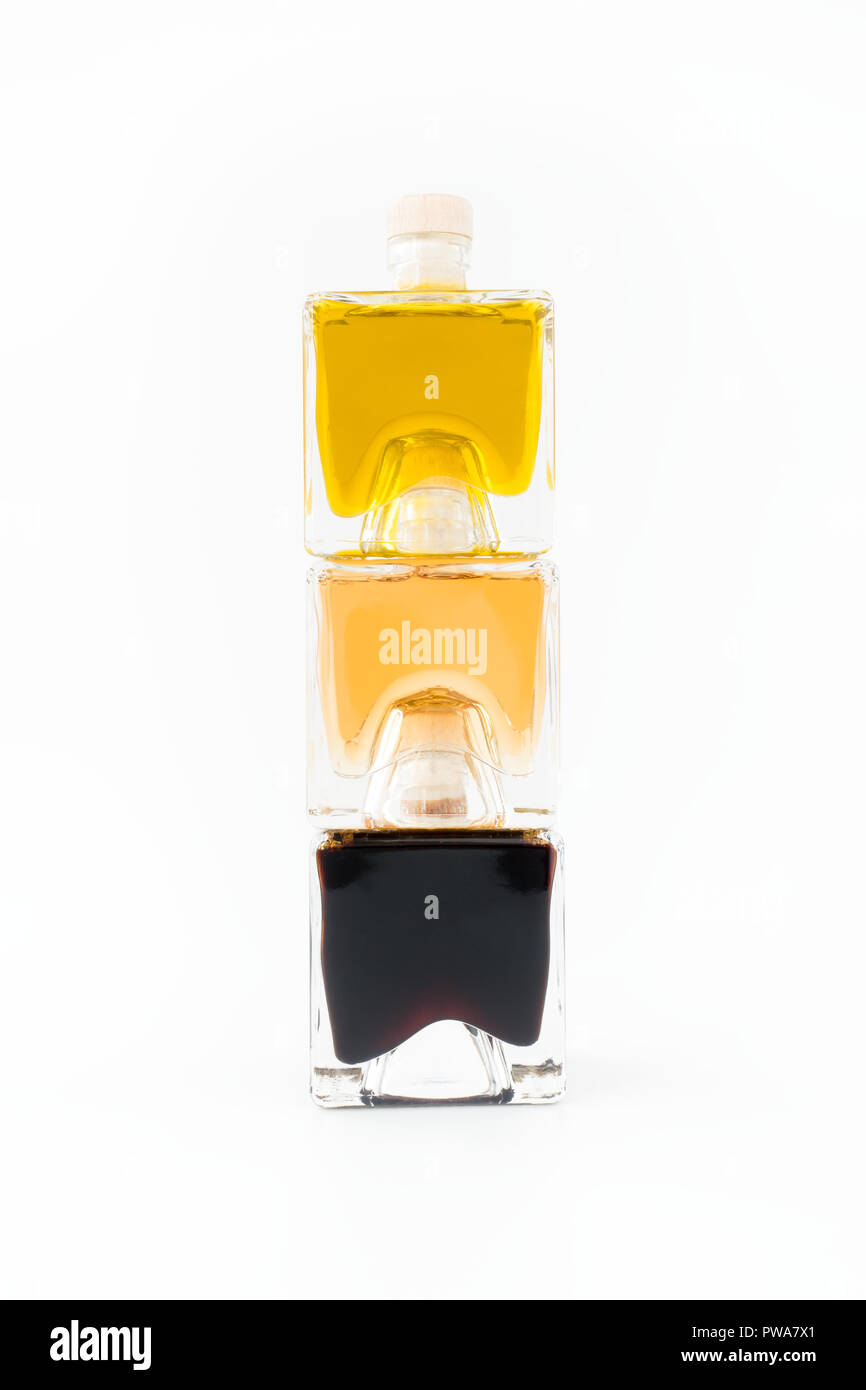 Trio of Balsamic Bianco, Balsamic Vinegar of Modena and Extra Virgin Olive Oil in square glass bottles on white background. Stock Photo