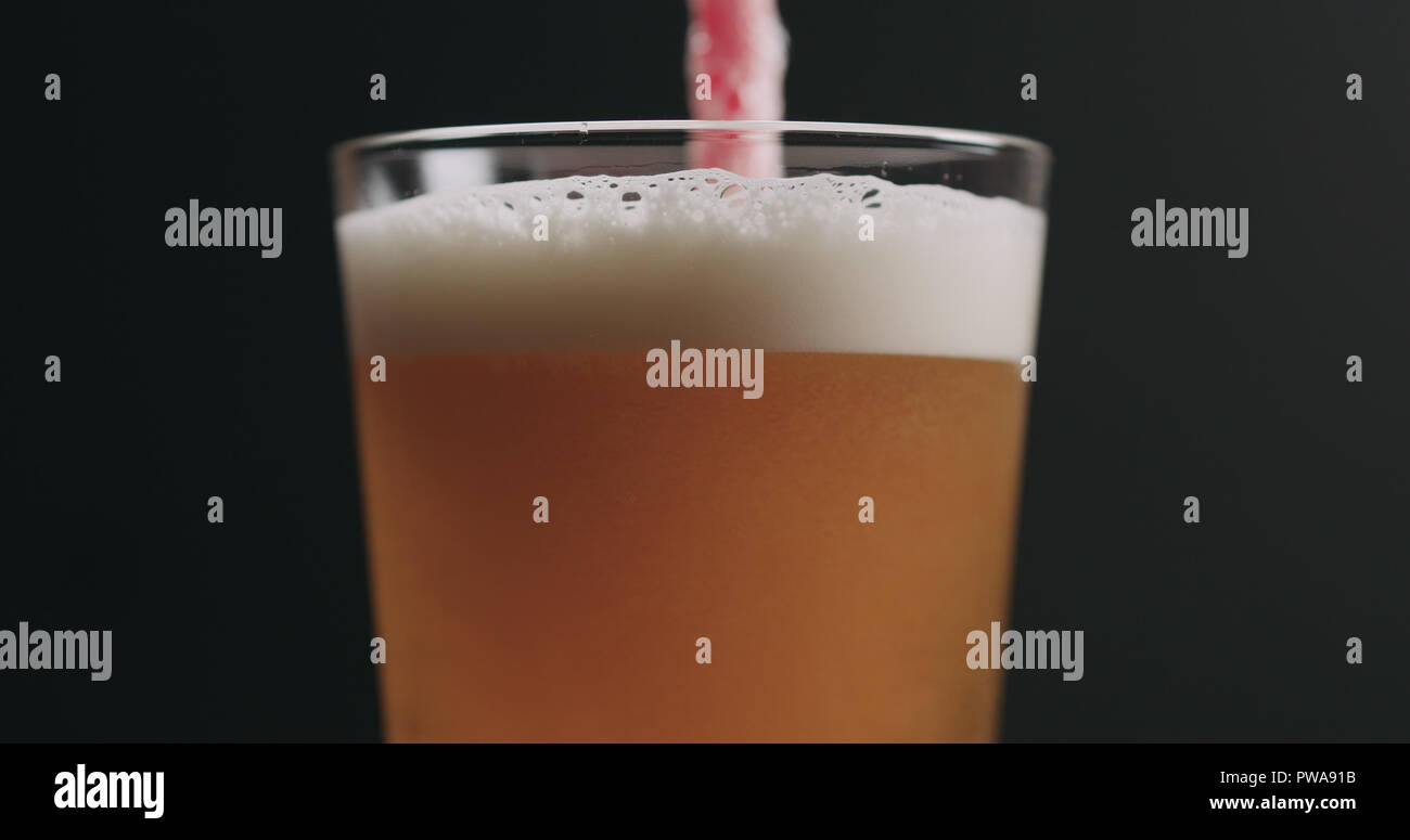 Closeup swirl light ale beer with bubbles over black background, wide