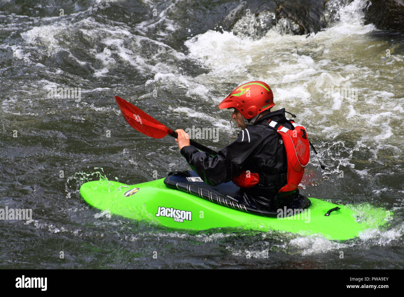 Man canoeing kayaking  white water rafting  wearing safety helmet hat on the river Derwent at Matlock Derbyshire England UK Stock Photo