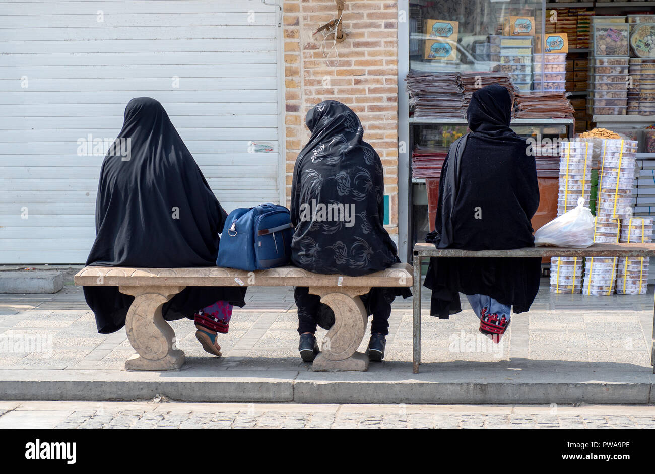 Yazd, Iran - March 7, 2017 : three women with islamic black chador sitting on benches Stock Photo