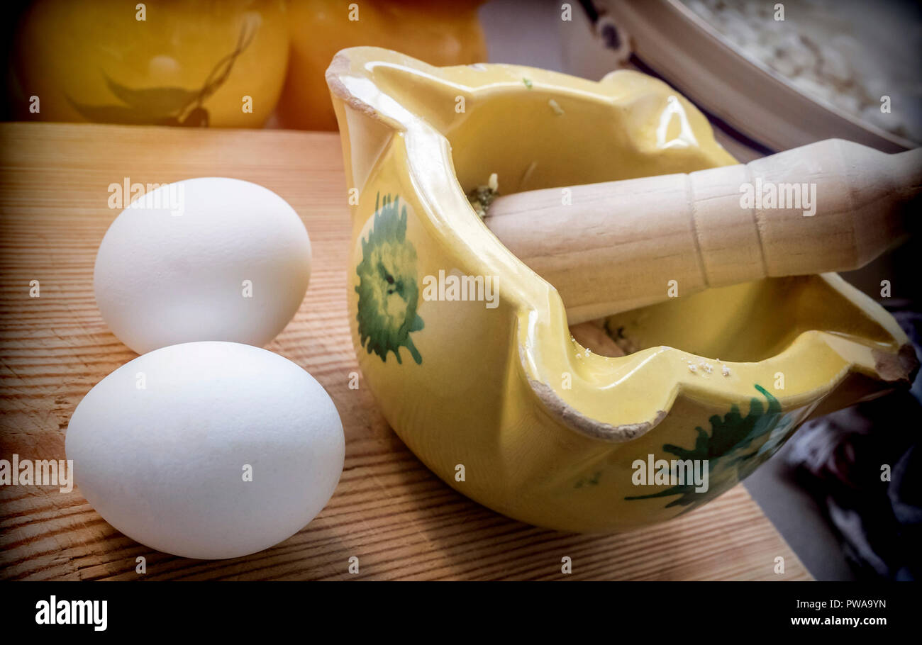 Traditional ceramic mortar with two white hen eggs in a kitchen, traditional cooking utensils Stock Photo