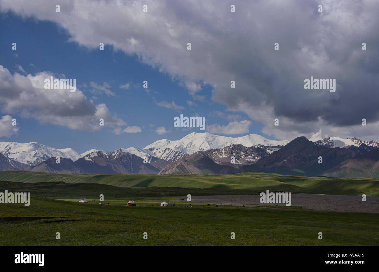 The High Pamirs rise over nomadic yurts along the Pamir Highway, Kyrgyzstan Stock Photo