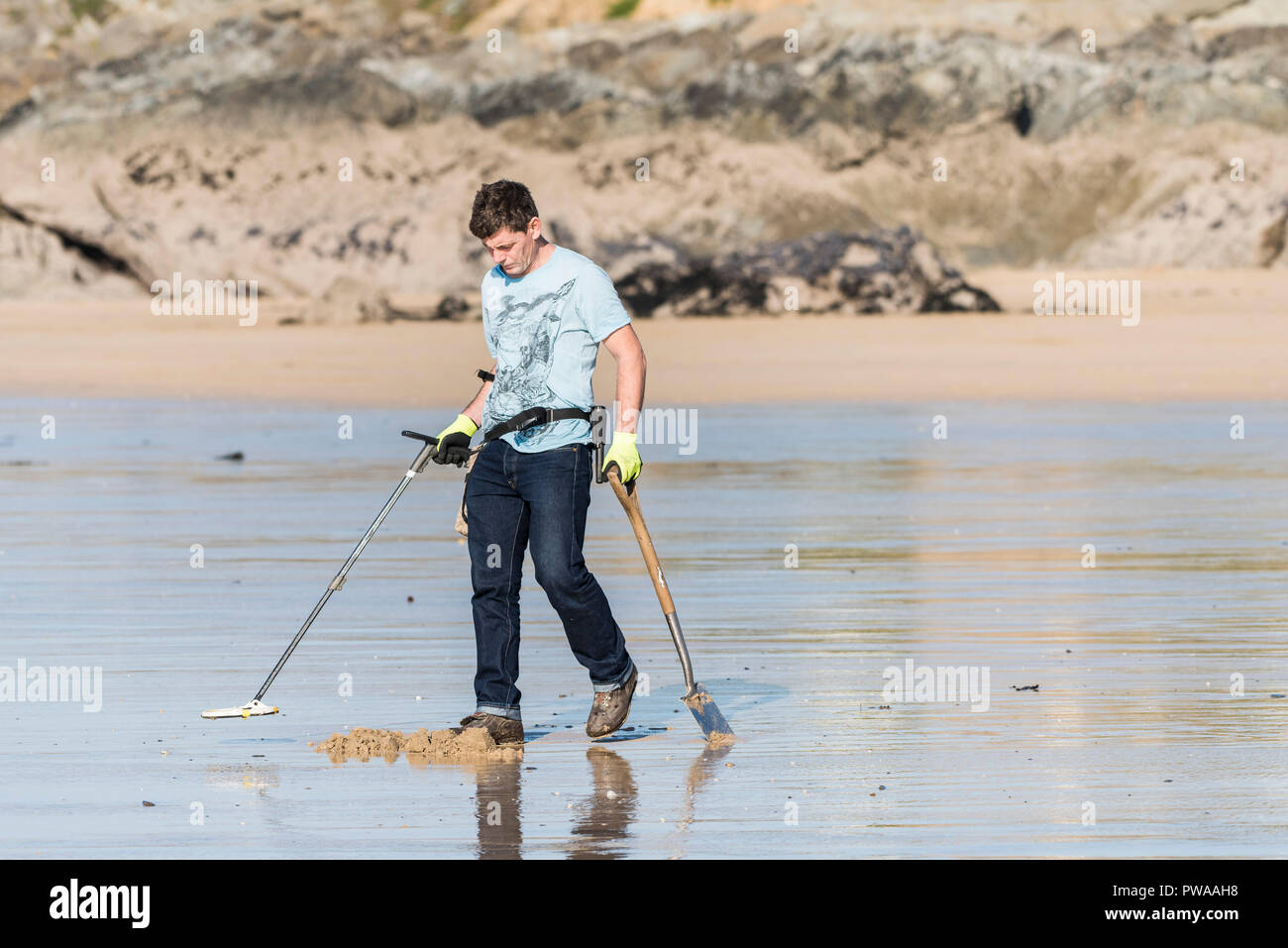 Metal detecting - A metal detectorist on Fistral Beach in Newquay in Cornwall. Stock Photo