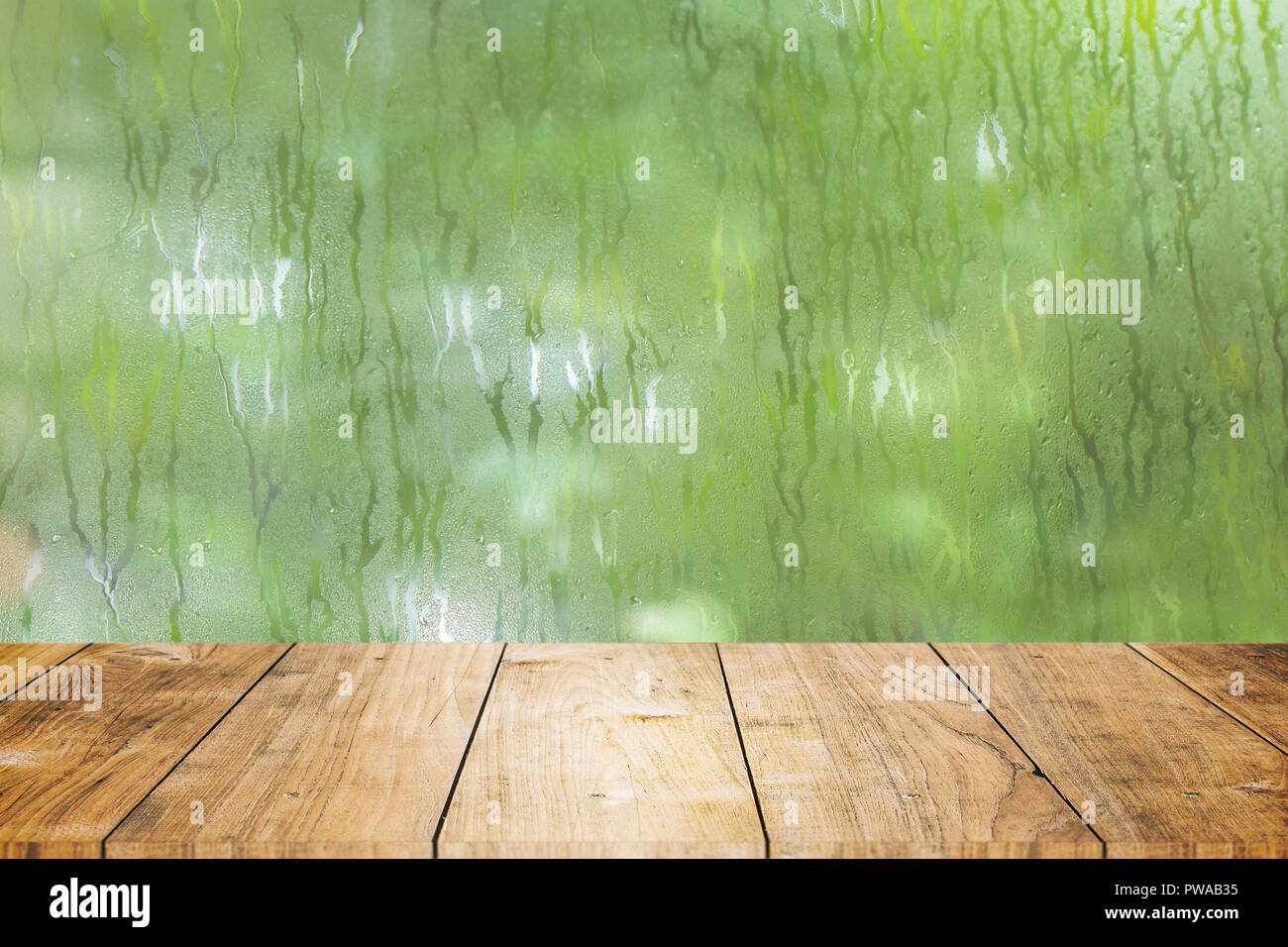blur fresh wet moist green nature with wooden table foreground space for products decoration montage. Stock Photo