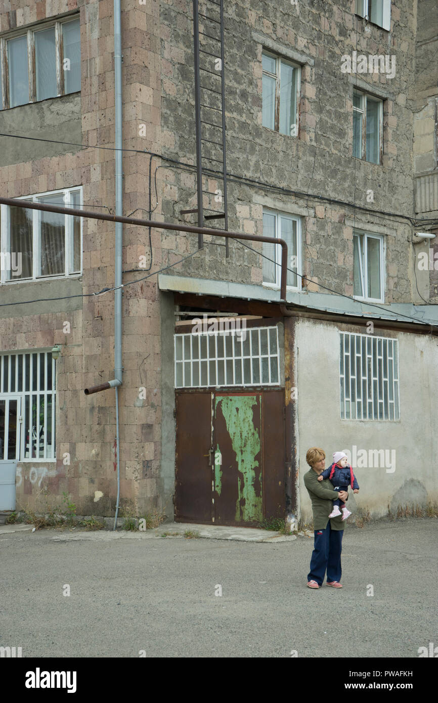 Mother with child outside in a run-down social housing block of ...