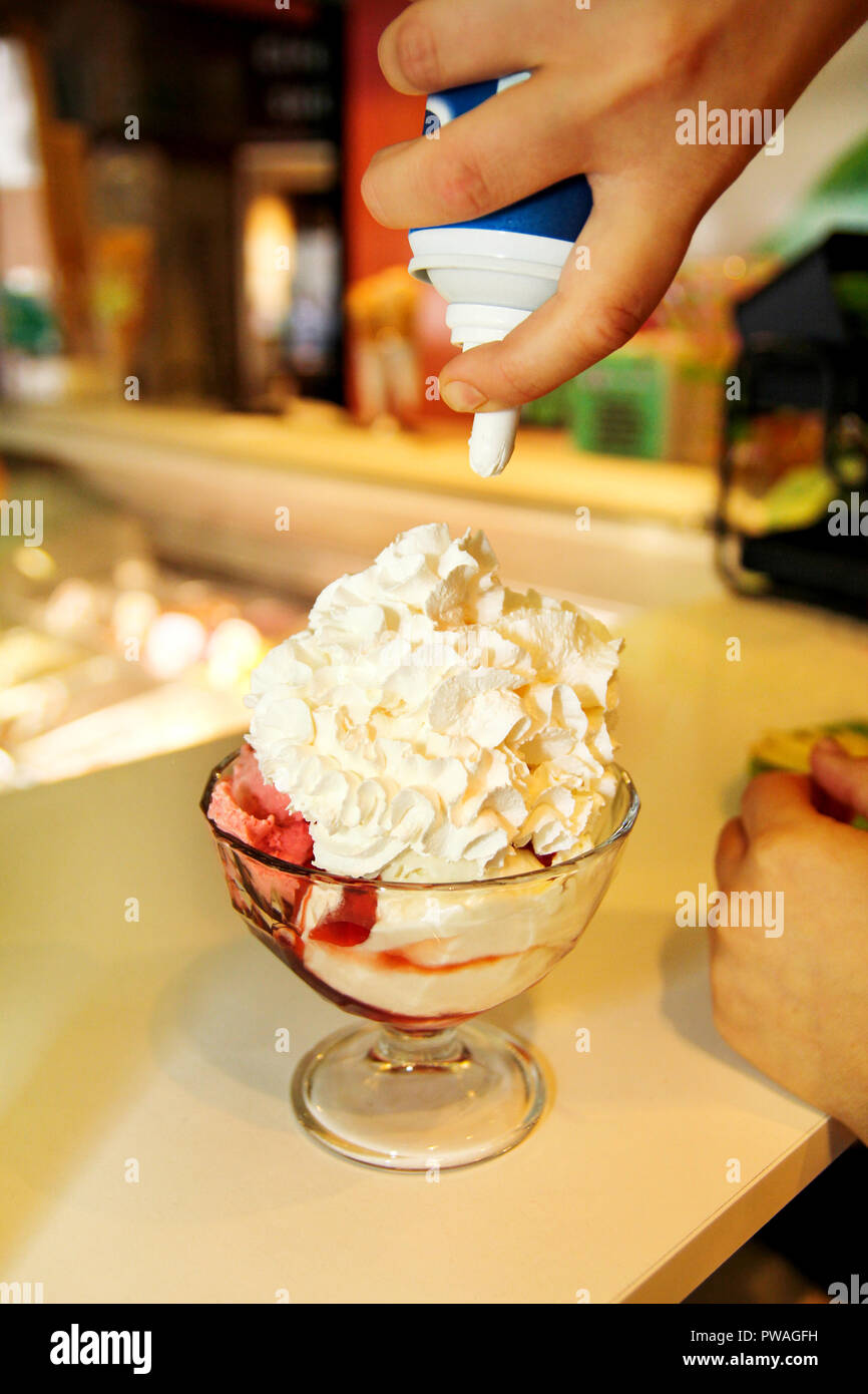 Female Seller pours sauce on ice cream. Woman hard making ice cream