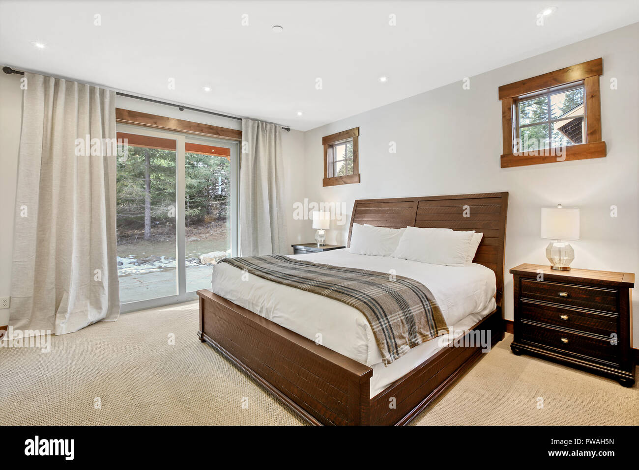 White bedroom interior with master bed and exit to back patio Stock