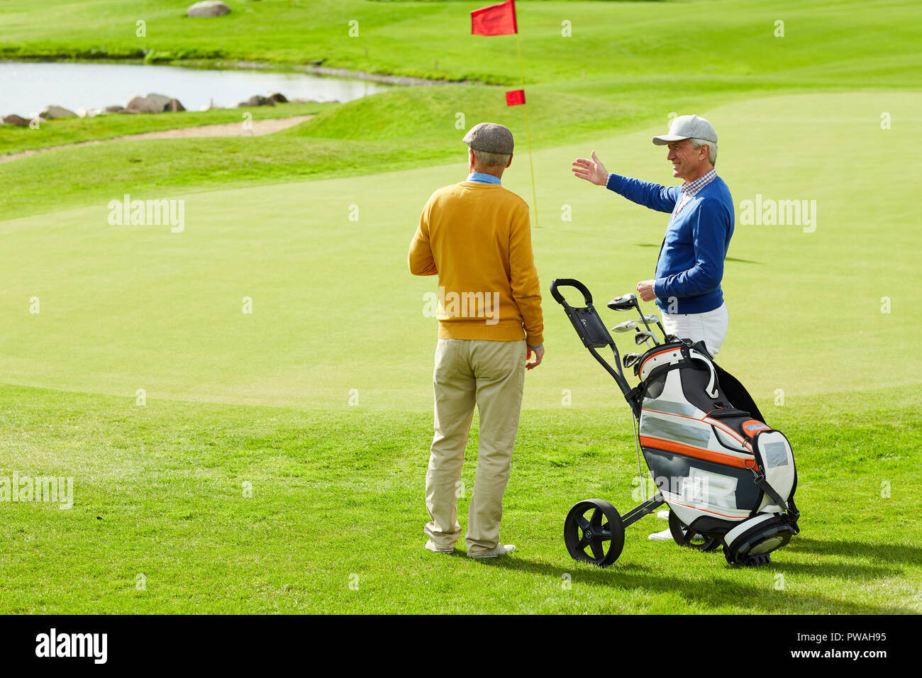 Two active senior man discussing small pond on play field while one of them pointing at it Stock Photo