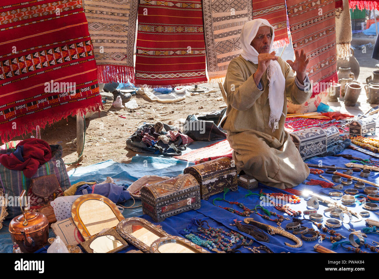 Morocco outdoor souk market. Merchant selling rugs and jewelry interacts with shoppers. Colorful image Stock Photo