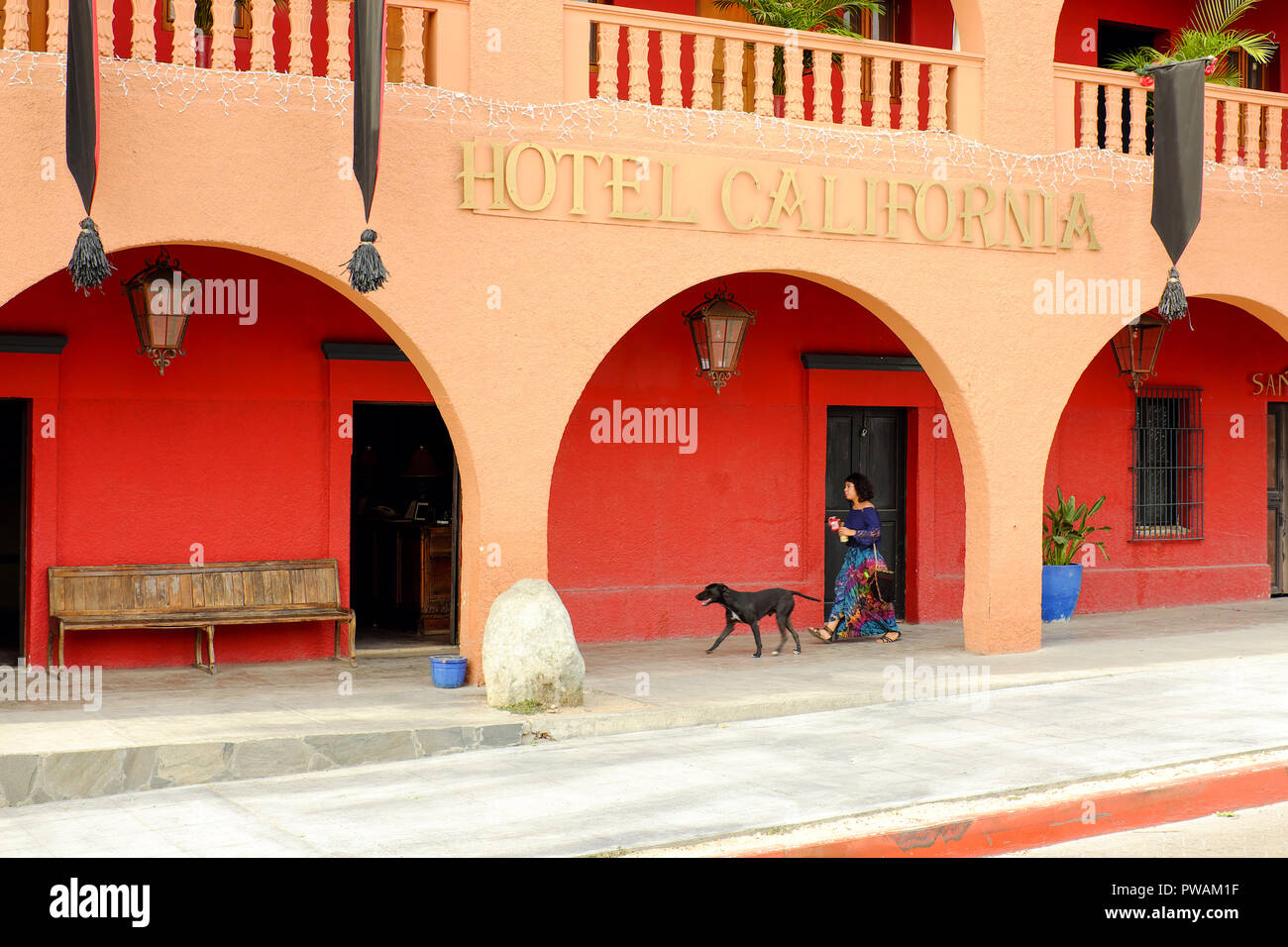 A woman and her dog walk past the Hotel California in Todos Santos, Mexico. Stock Photo