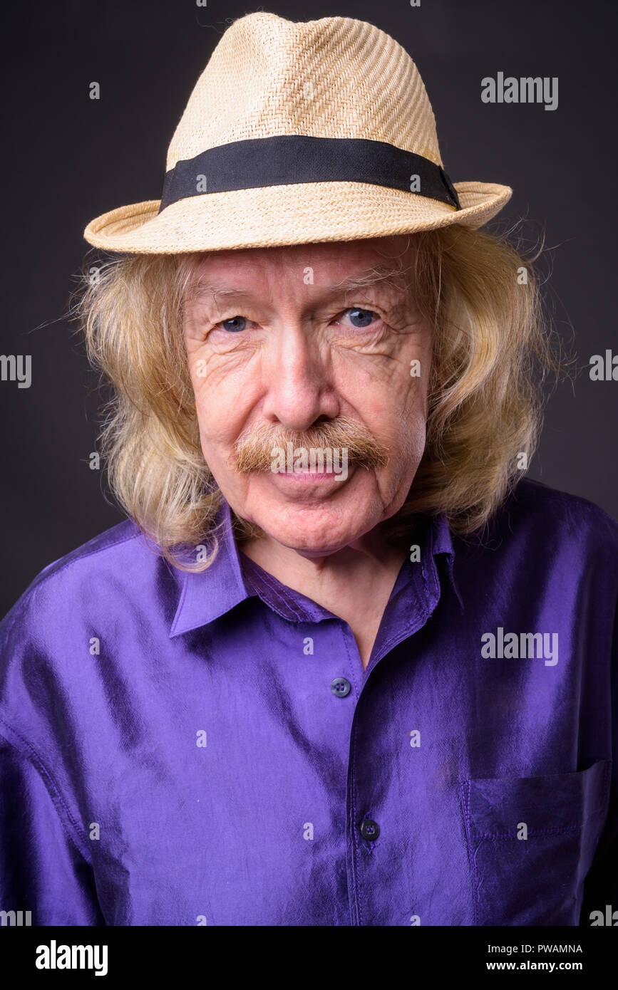 Senior tourist man with mustache against gray background Stock Photo