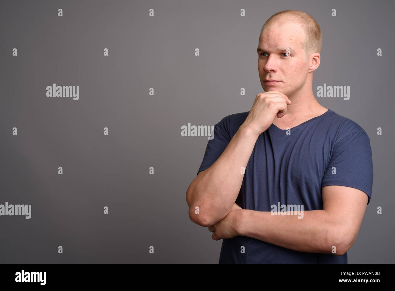 Bald man wearing blue shirt against gray background Stock Photo
