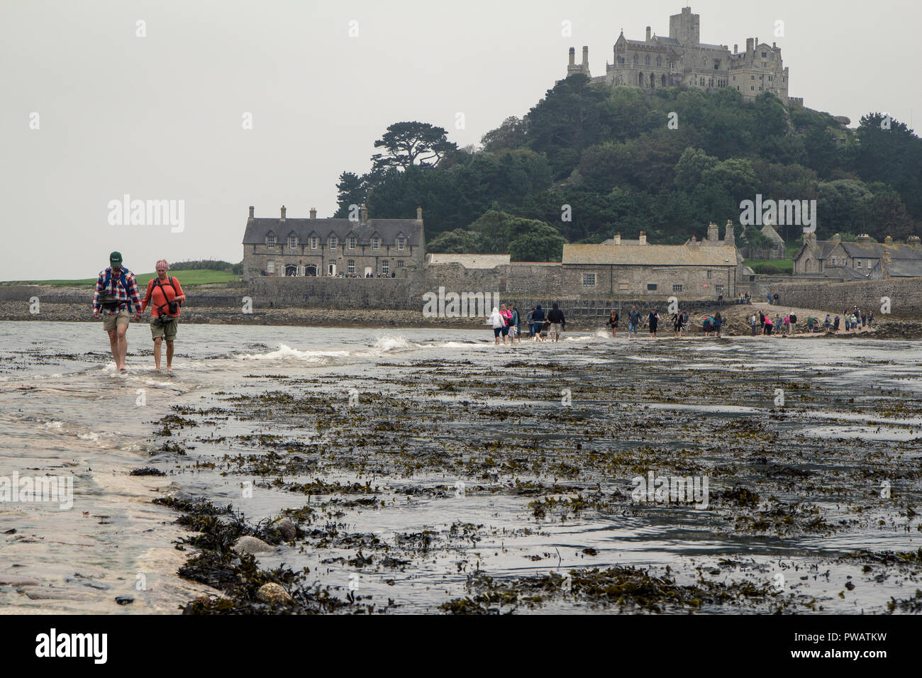 Tourists crossing the causeway to St. Michael's Mount while it becomes flooded by the high tide, Cornwall, UK Stock Photo