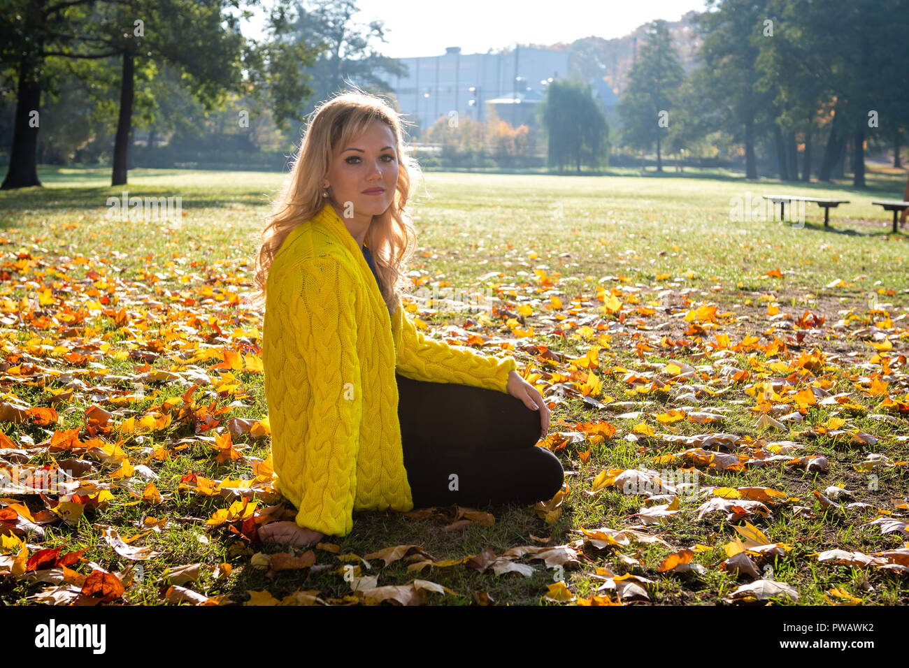 A young, beautiful, blonde woman walking through the autumn park and ...