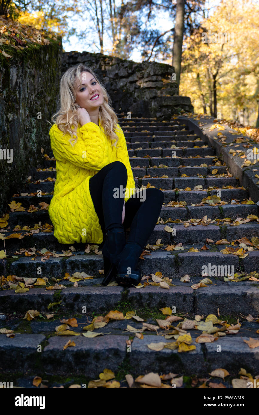 Young Beautiful Blonde Woman Sits In The Park On A Old Ladder Young Beautiful Blonde Woman Sits In The Park On A Old Ladder