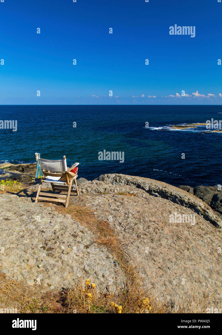 Beautiful landscape with wooden chair on rocky shore Stock Photo - Alamy