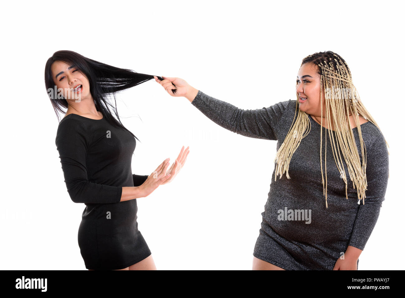 Young happy fat Asian woman smiling while pulling hair of Asian  Stock Photo