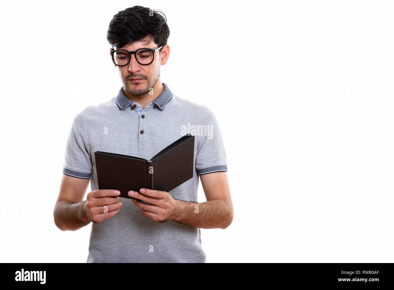 Studio shot of young Persian man reading book Stock Photo