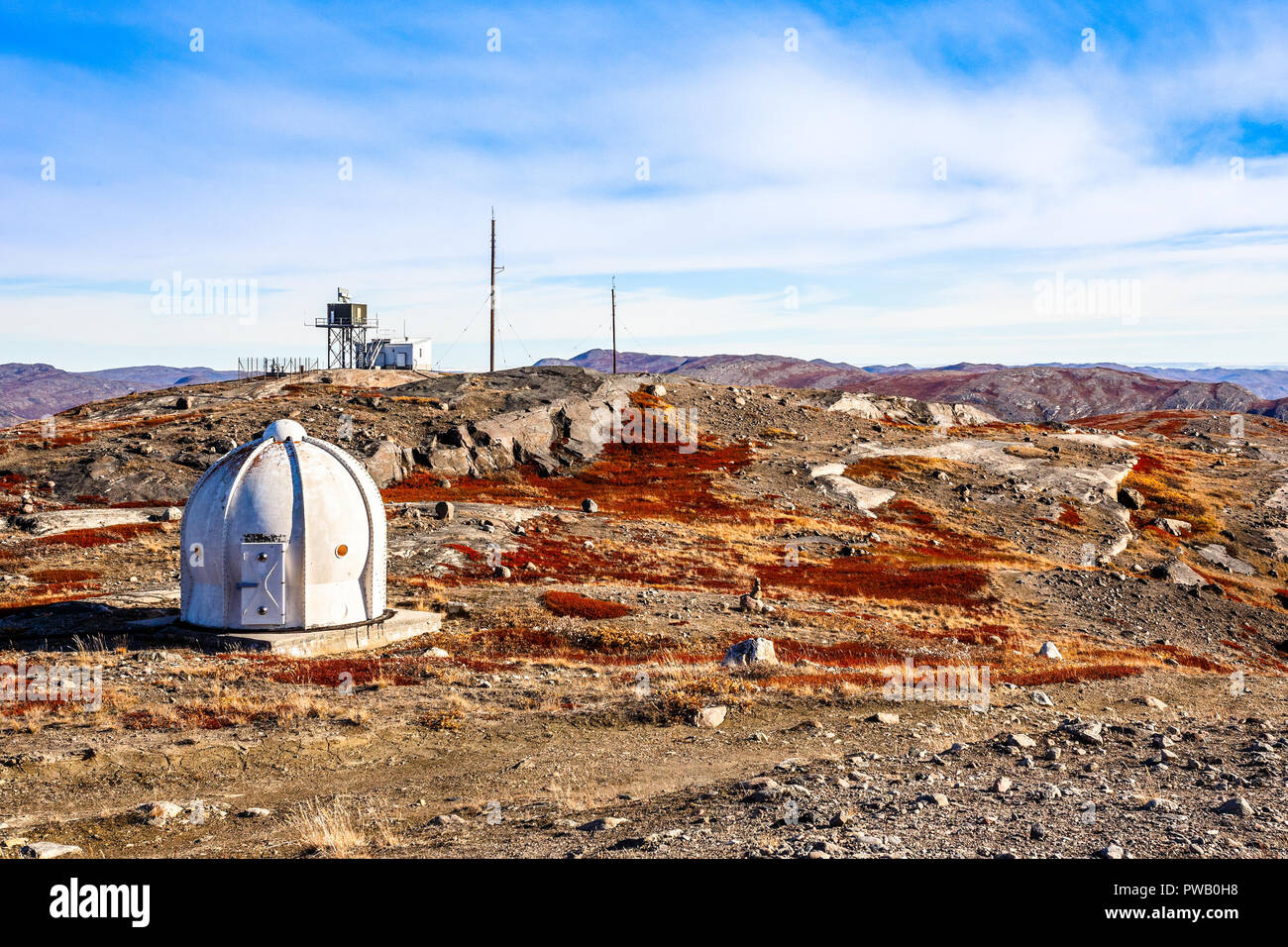 Metal bunker with meteorologic station and autumn greenlandic orange tundra landscape with mountains in the background, Kangerlussuaq, Greenland Stock Photo