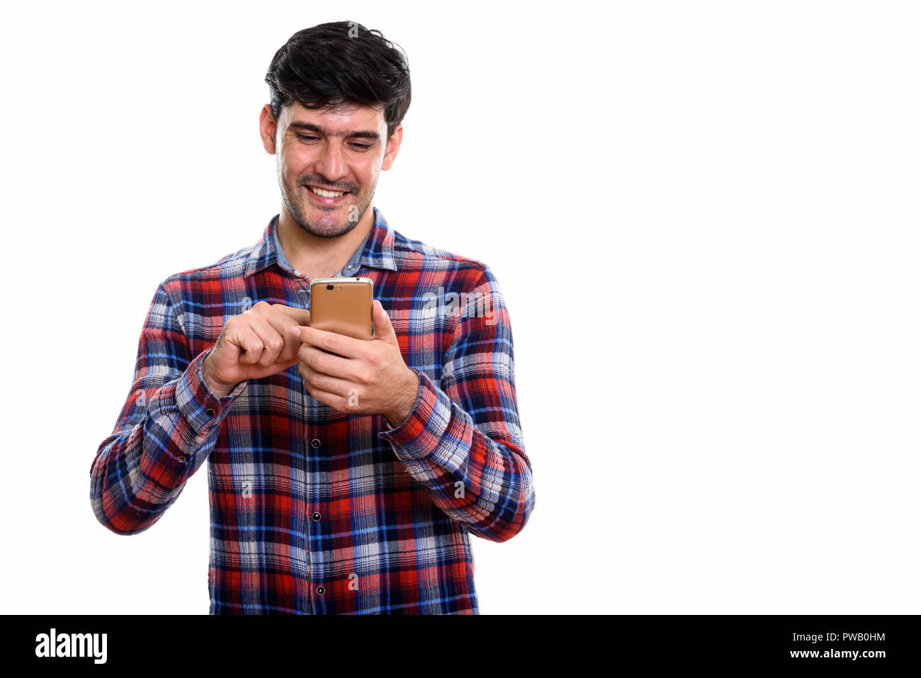 Using Mobile Stock Photo Studio shot of young happy Persian man smiling while using mobil Stock ...