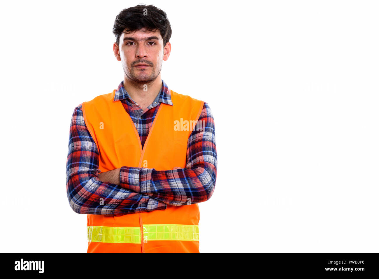 Studio shot of young Persian man construction worker with arms c Stock Photo