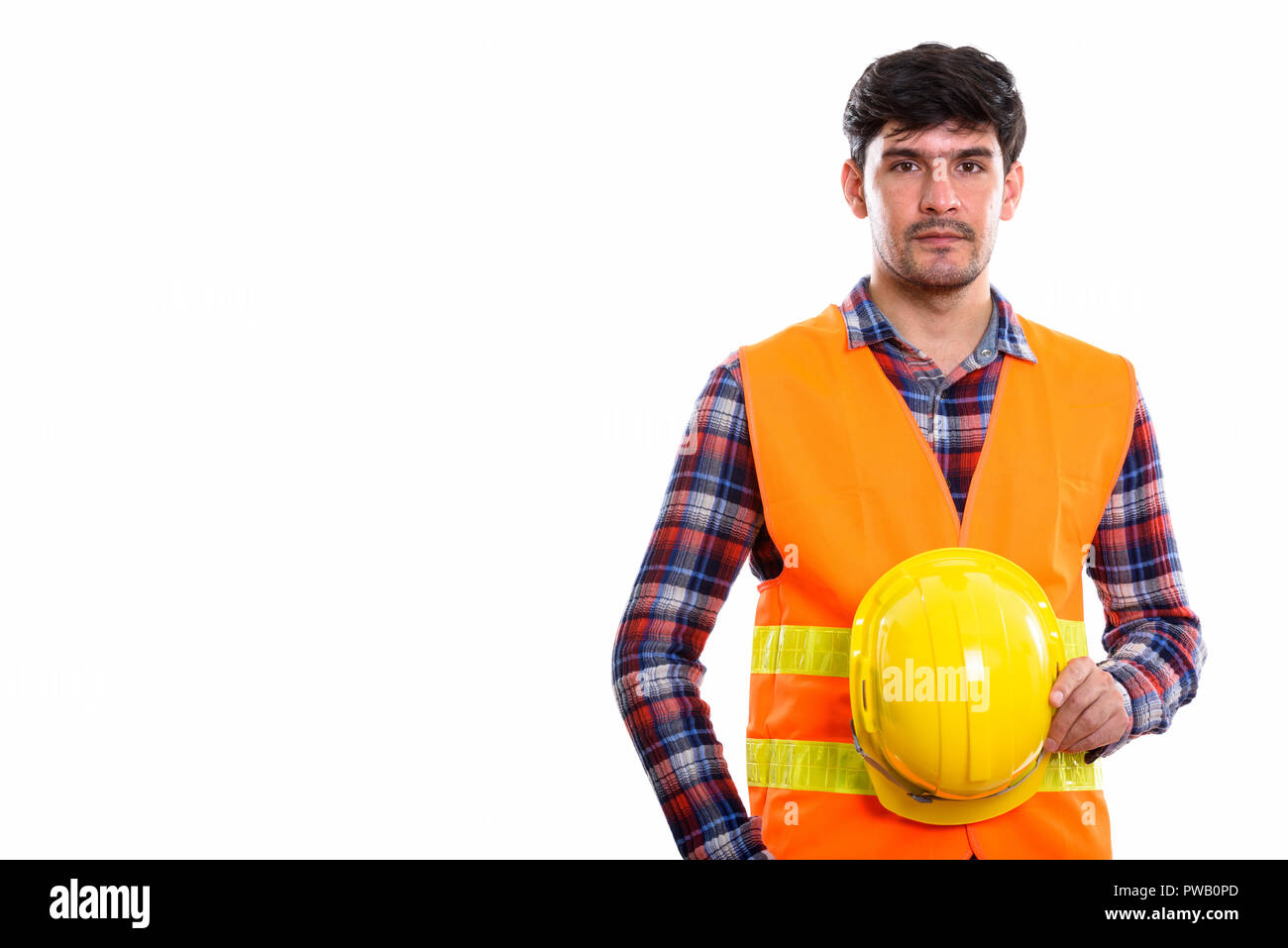 Studio shot of young Persian man construction worker holding saf Stock Photo