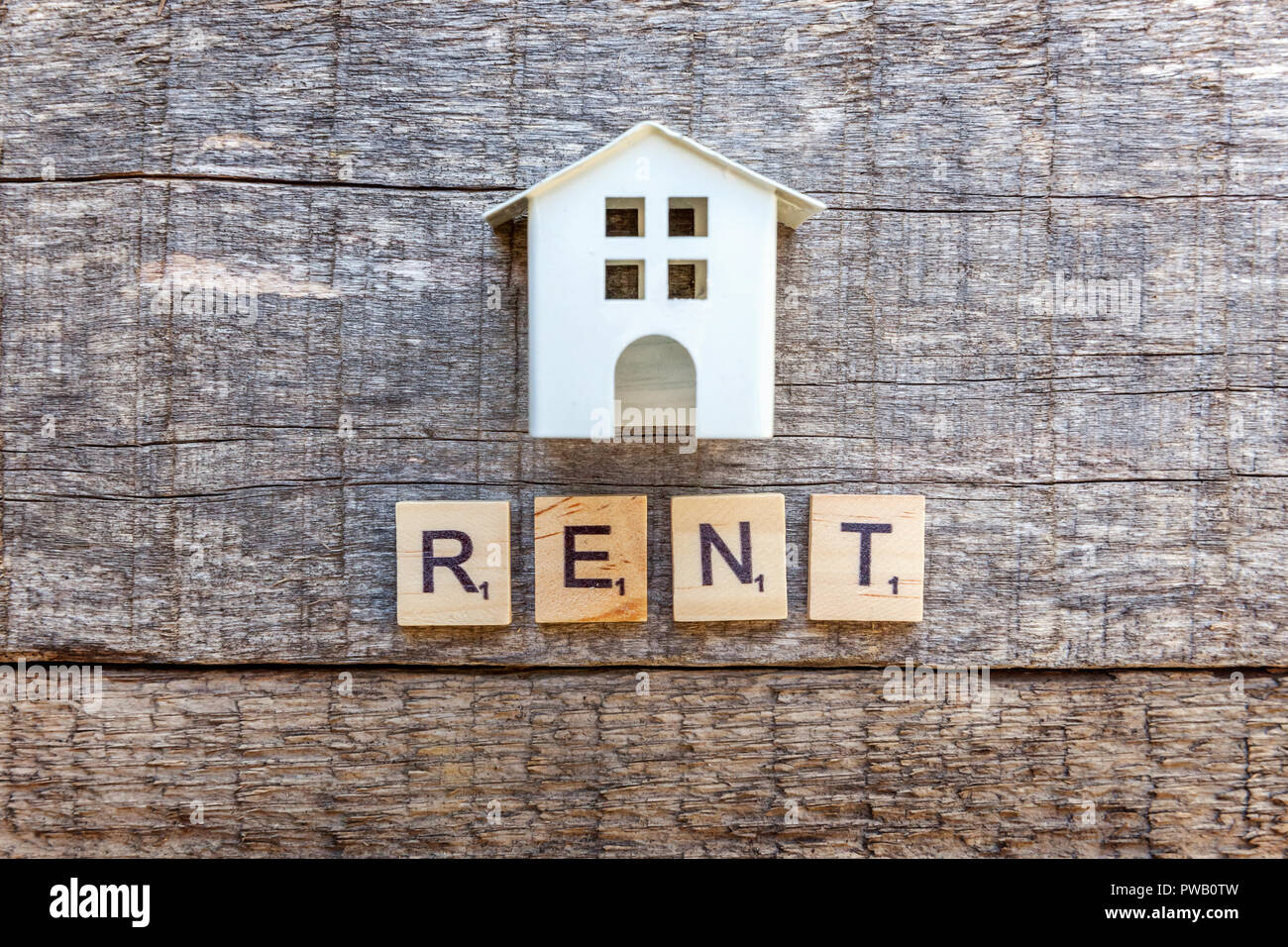 Miniature toy model house with inscription RENT letters word on wooden ...