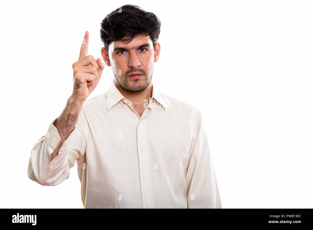 Studio shot of young Persian businessman pointing finger up Stock Photo