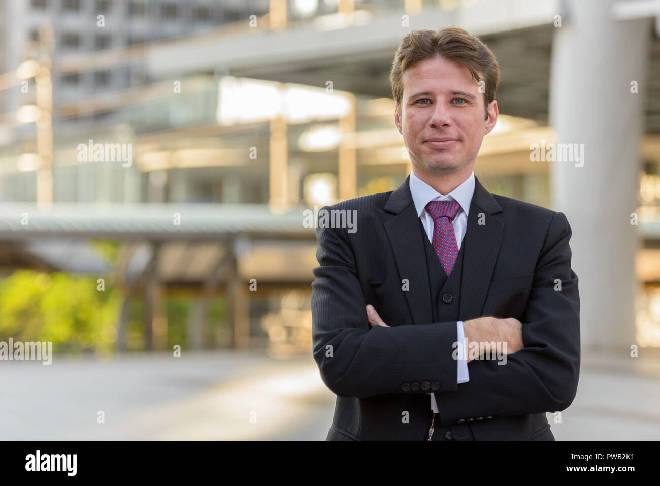 Businessman with arms crossed in front of modern building at Ban Stock ...