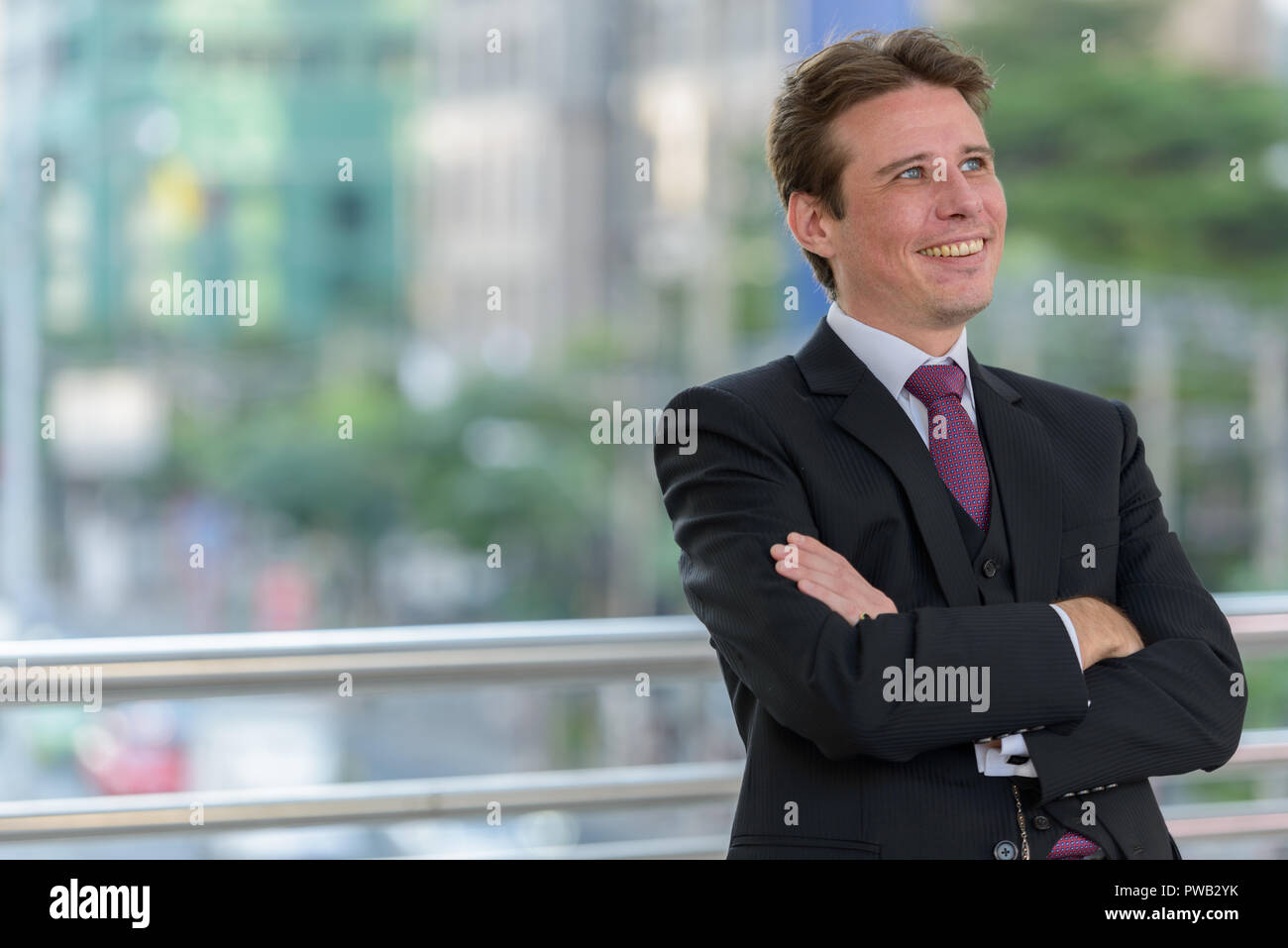 Happy businessman smiling and thinking with arms crossed on foot Stock ...