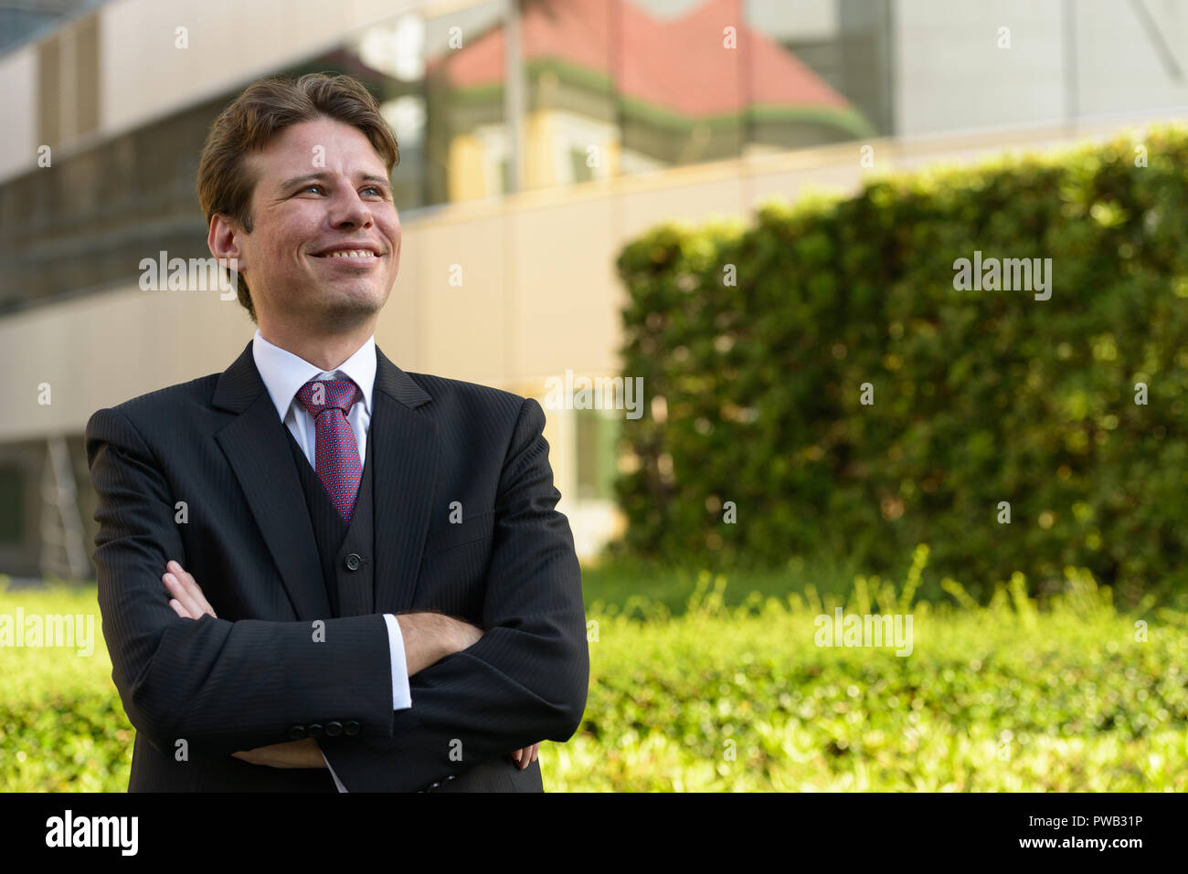Happy businessman smiling and thinking with arms crossed in fron Stock ...
