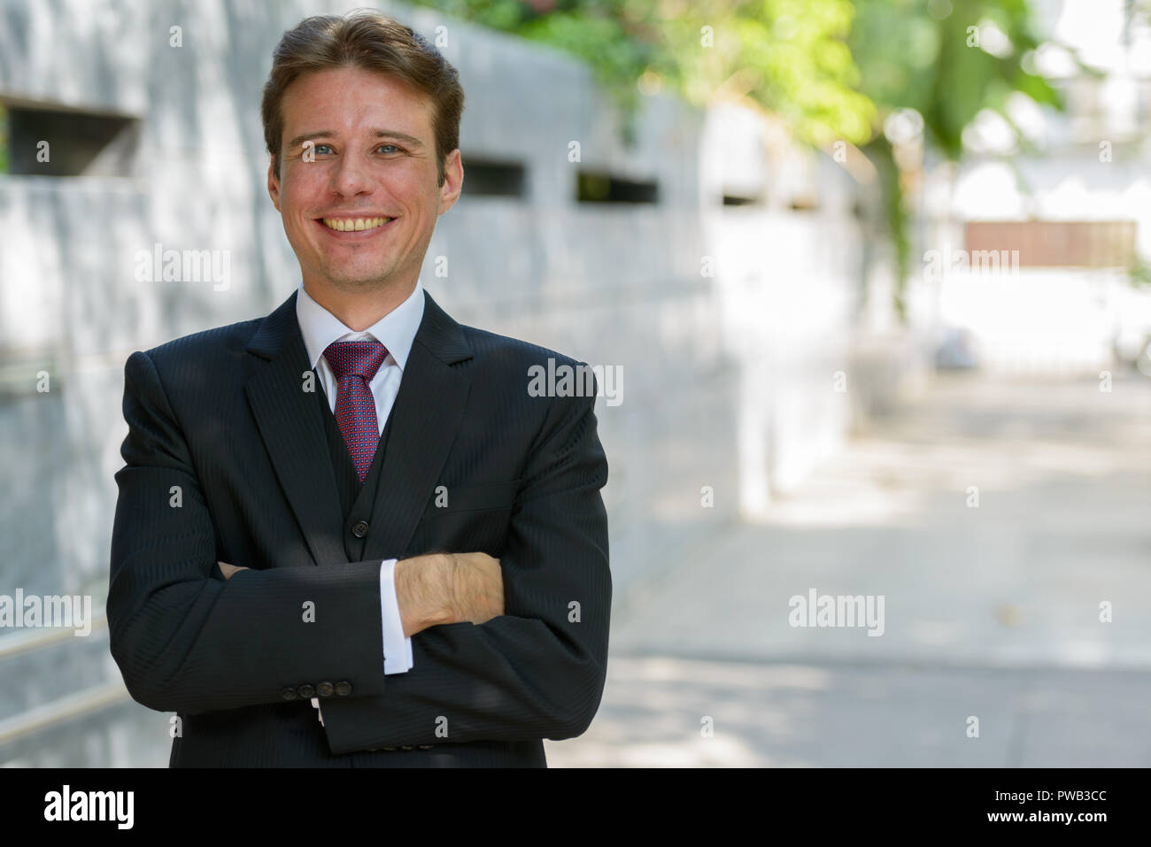 Happy businessman smiling with arms crossed outdoors at Bangkok Stock ...