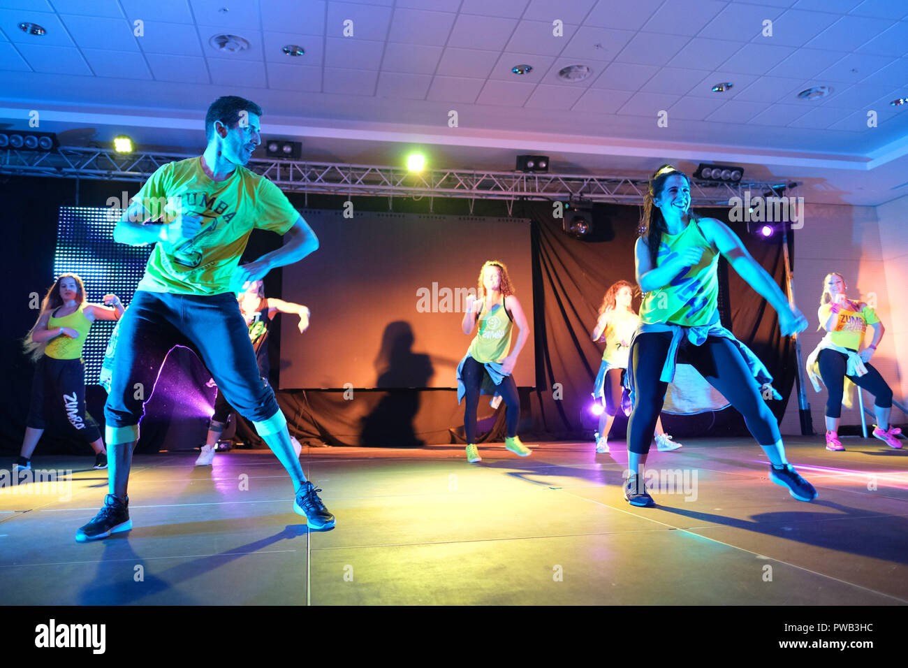 Instructors dancing energetically on stage during a Zumba class Stock Photo