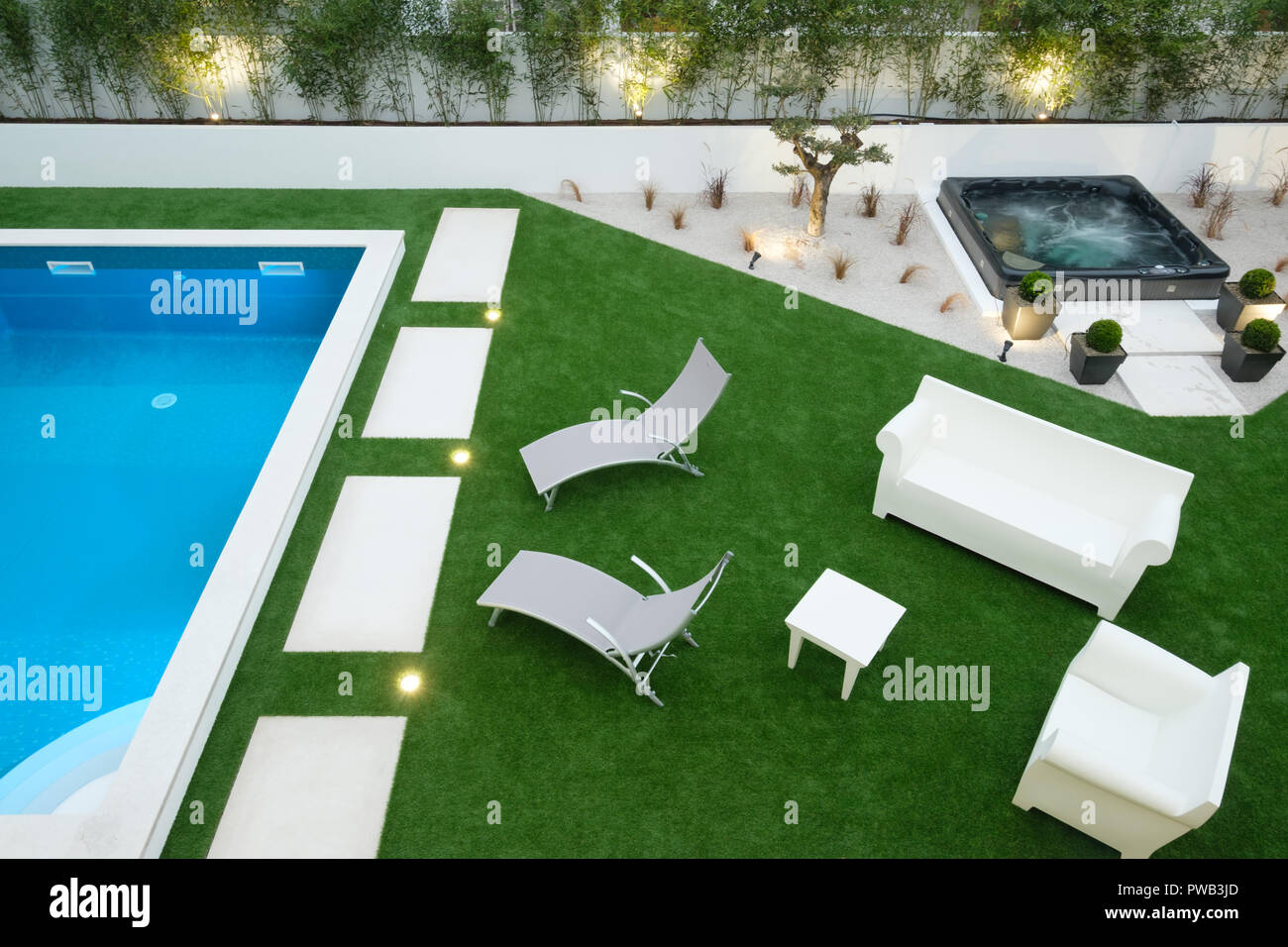 Aerial view of a backyard with a swimming pool, a jacuzzi, two deckchairs and assorted outdoors furniture Stock Photo