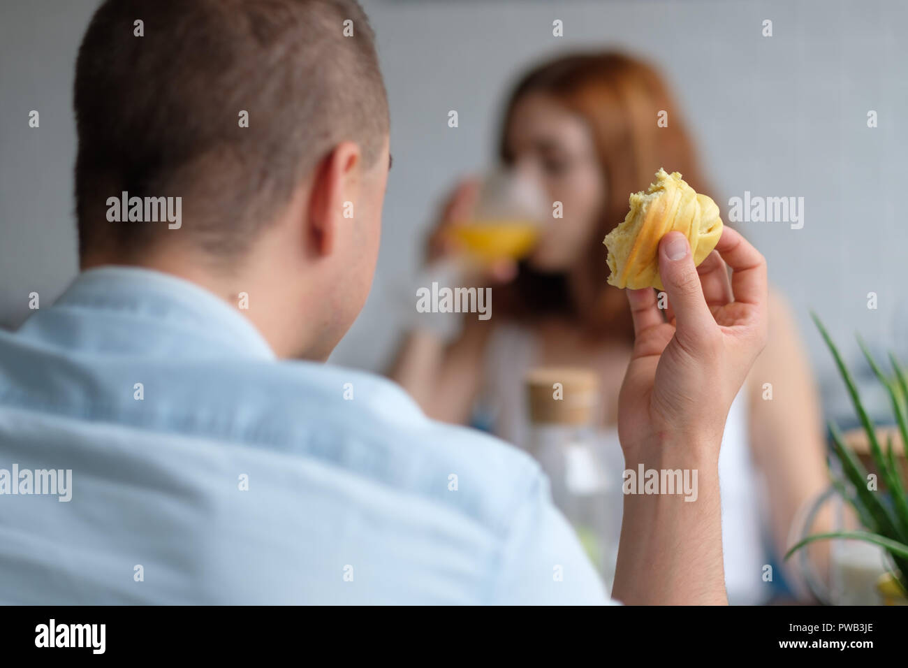Selective focus photo of two people eating a croissant and drinking orange juice for breakfast Stock Photo