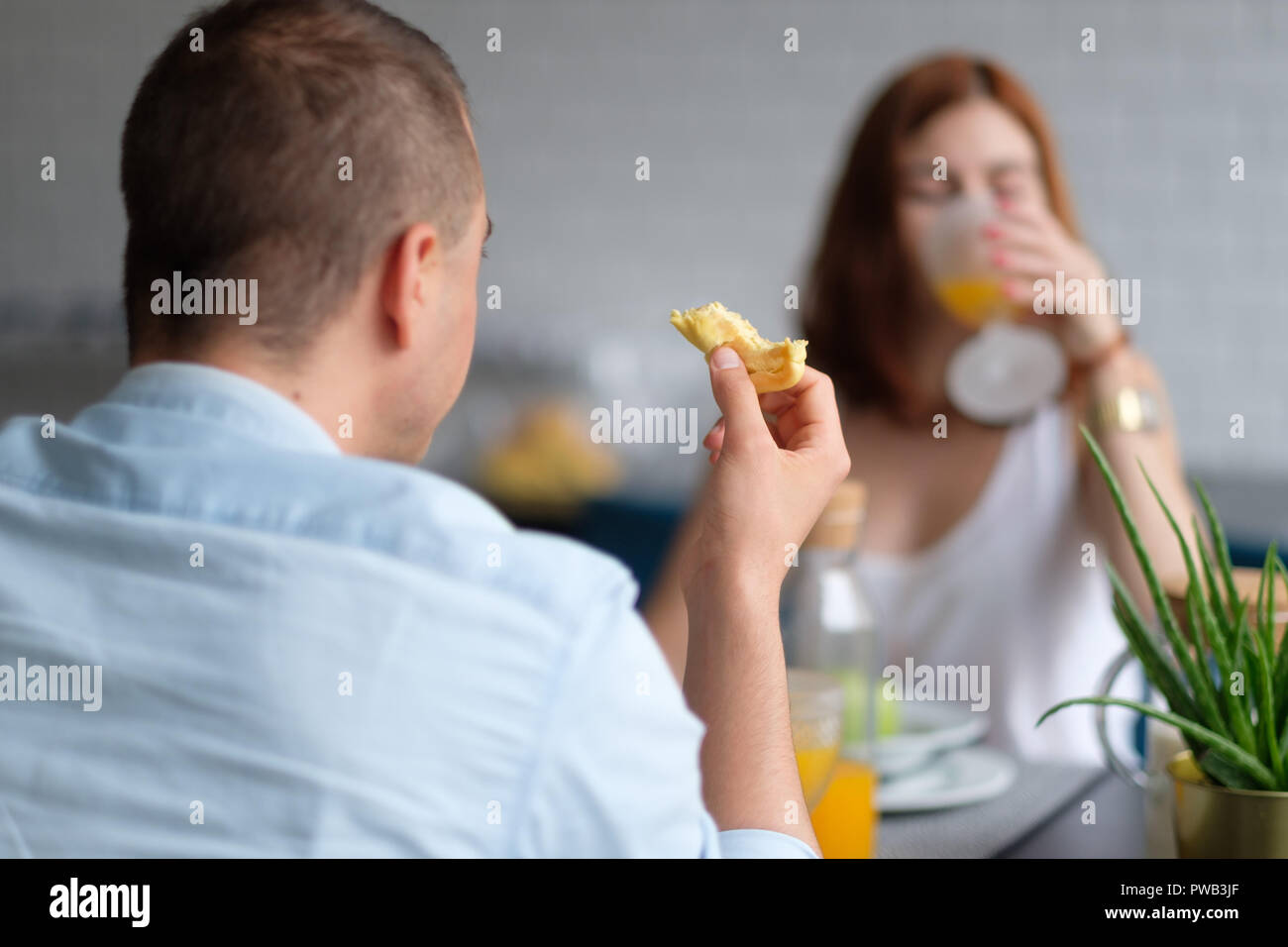 Selective focus photo of two people eating a croissant and drinking orange juice for breakfast Stock Photo