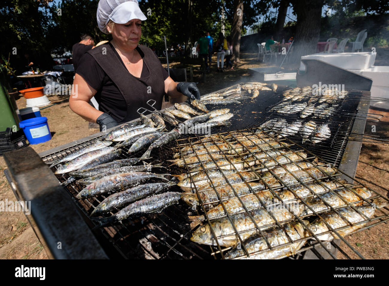 Woman cooking sardines on a grill outdoors Stock Photo