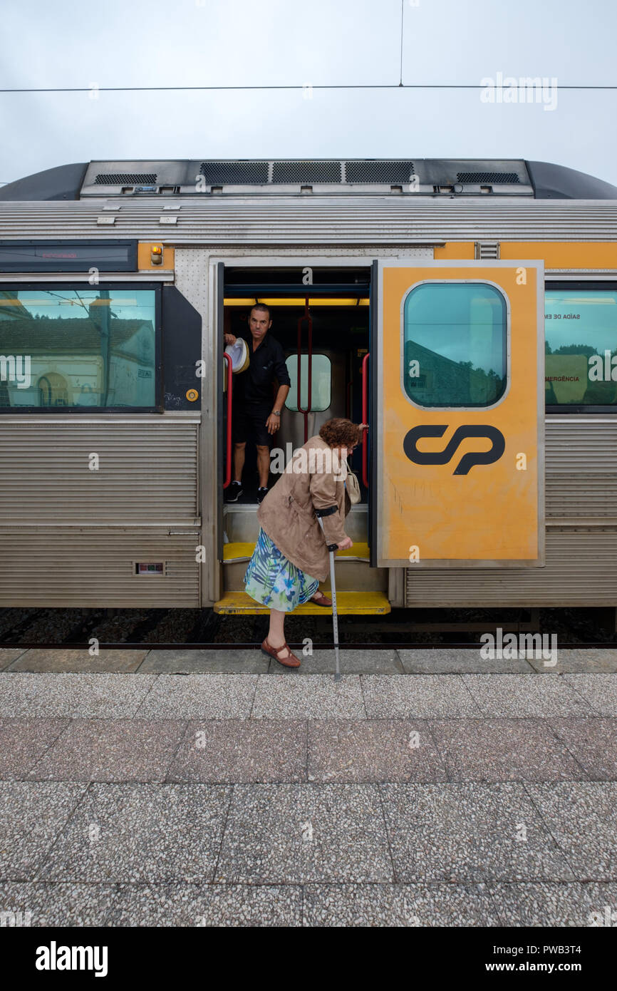 Old woman using a crutch getting off a train Stock Photo