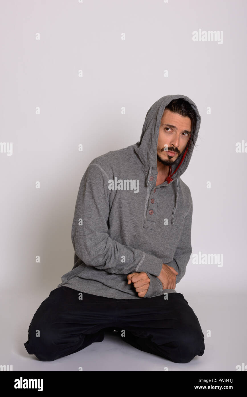 Studio shot of handsome man looking scared while kneeling Stock Photo
