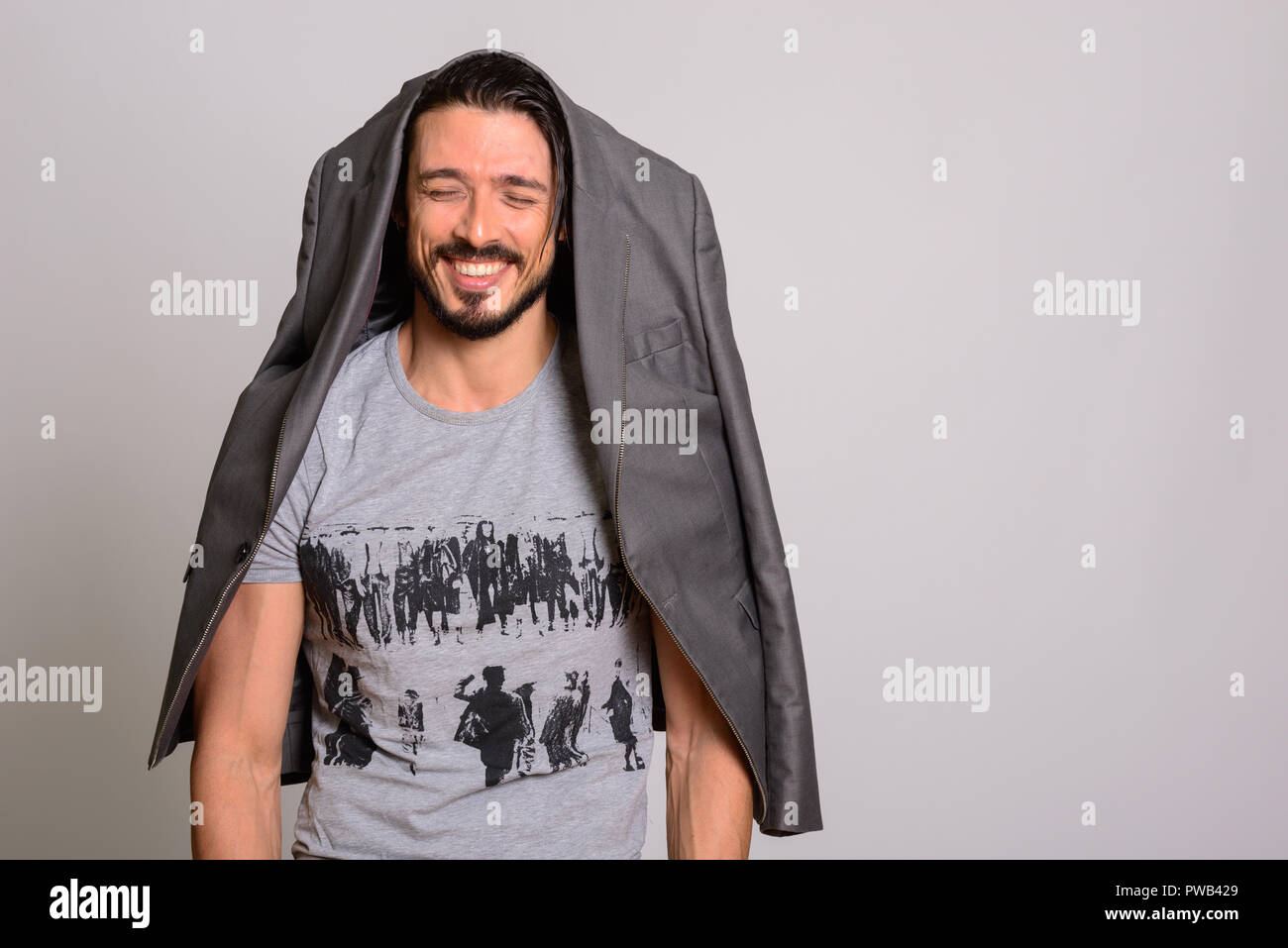Studio shot of happy handsome man smiling with jacket hanging on Stock Photo