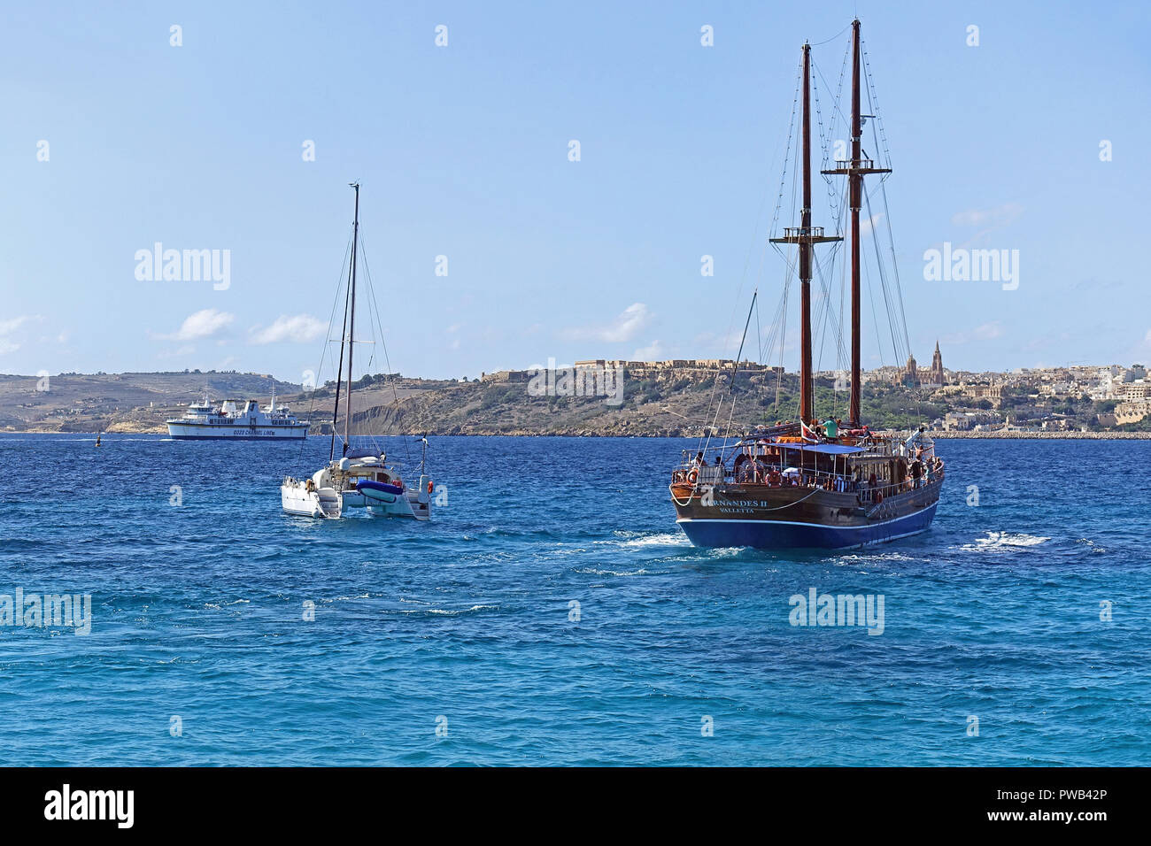 Boats head out from Blue Lagoon, Comino Island, Malta, after a day of swimming and diving in the crystal-clear water. Stock Photo