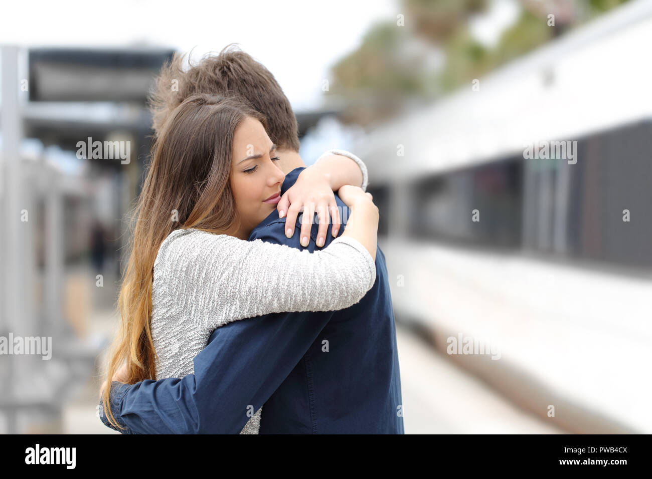 Sad couple hugging saying goodbye before train travel Stock Photo