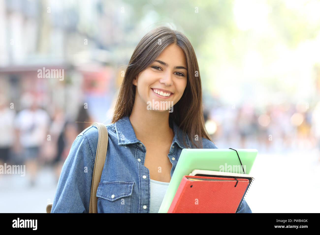 Happy student holding folders poses looking at camera in the street Stock Photo