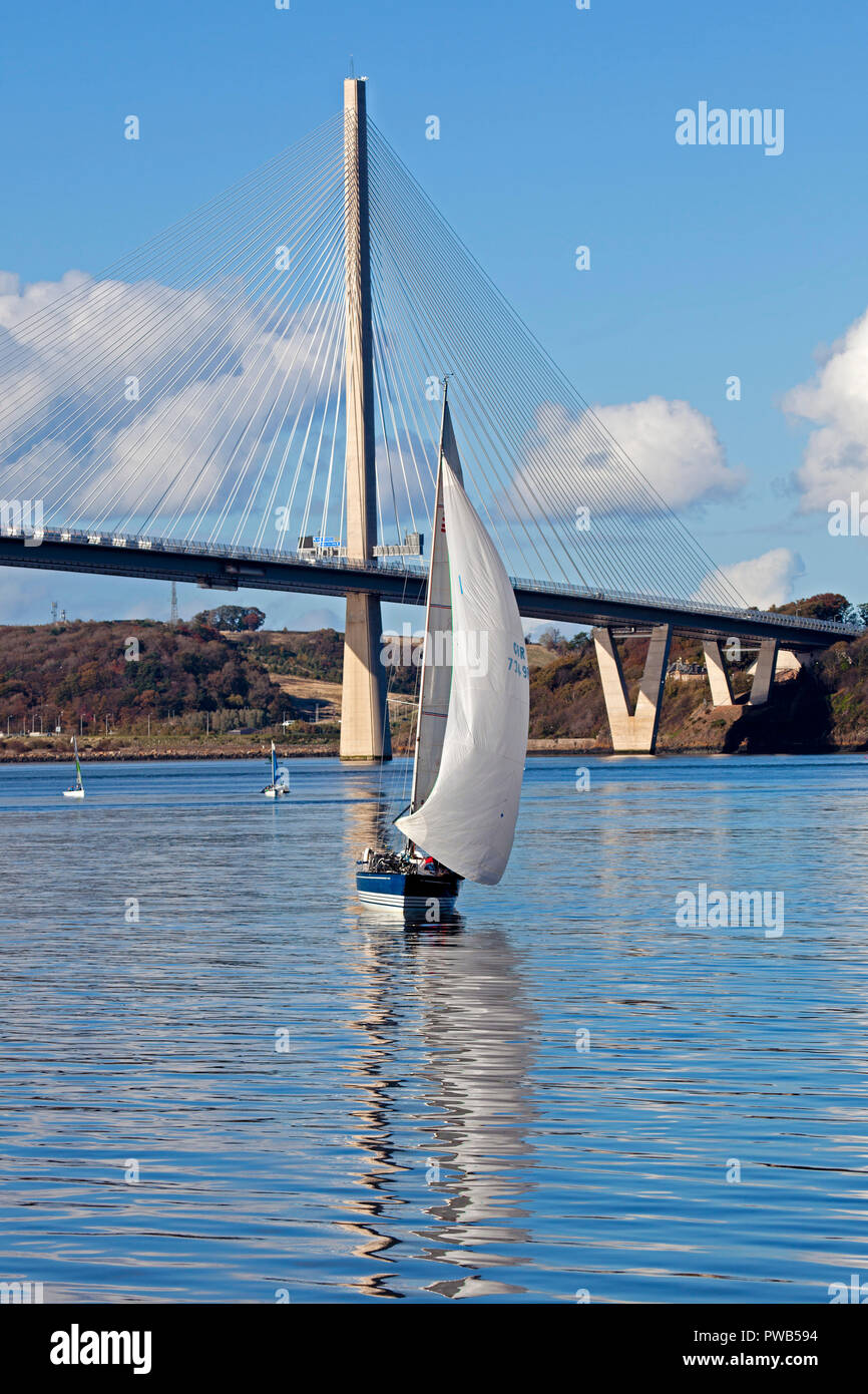 Edinburgh, Scotland, UK. 14 October 2018. UK weather, after a very cloudy cold morning the sun appeared in early afternoon and at 13 degrees it felt warm in the sunshine, not much wind to assist the crews of the small sail boats in the Forth estuary under the Queensferry Crossing Bridge on a gorgeous afternoon for the sailing. Stock Photo
