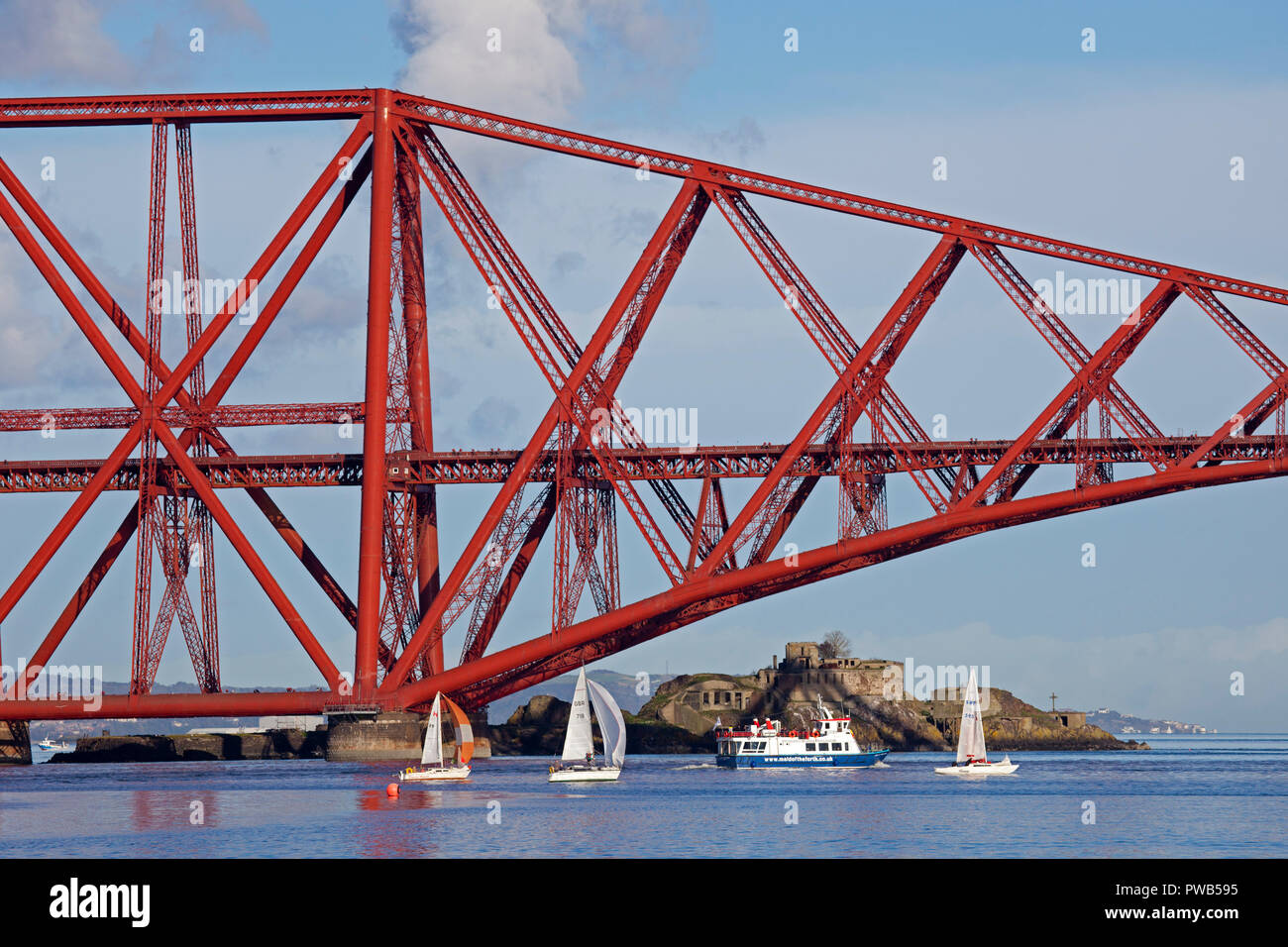 Edinburgh, Scotland, UK. 14 October 2018. UK weather, after a very cloudy cold morning the sun appeared in early afternoon and at 13 degrees it felt warm in the sunshine, not much wind to assist the crews of the small sail boats in the Forth estuary under the Forth Rail Bridge on a gorgeous afternoon for the sailing. Stock Photo