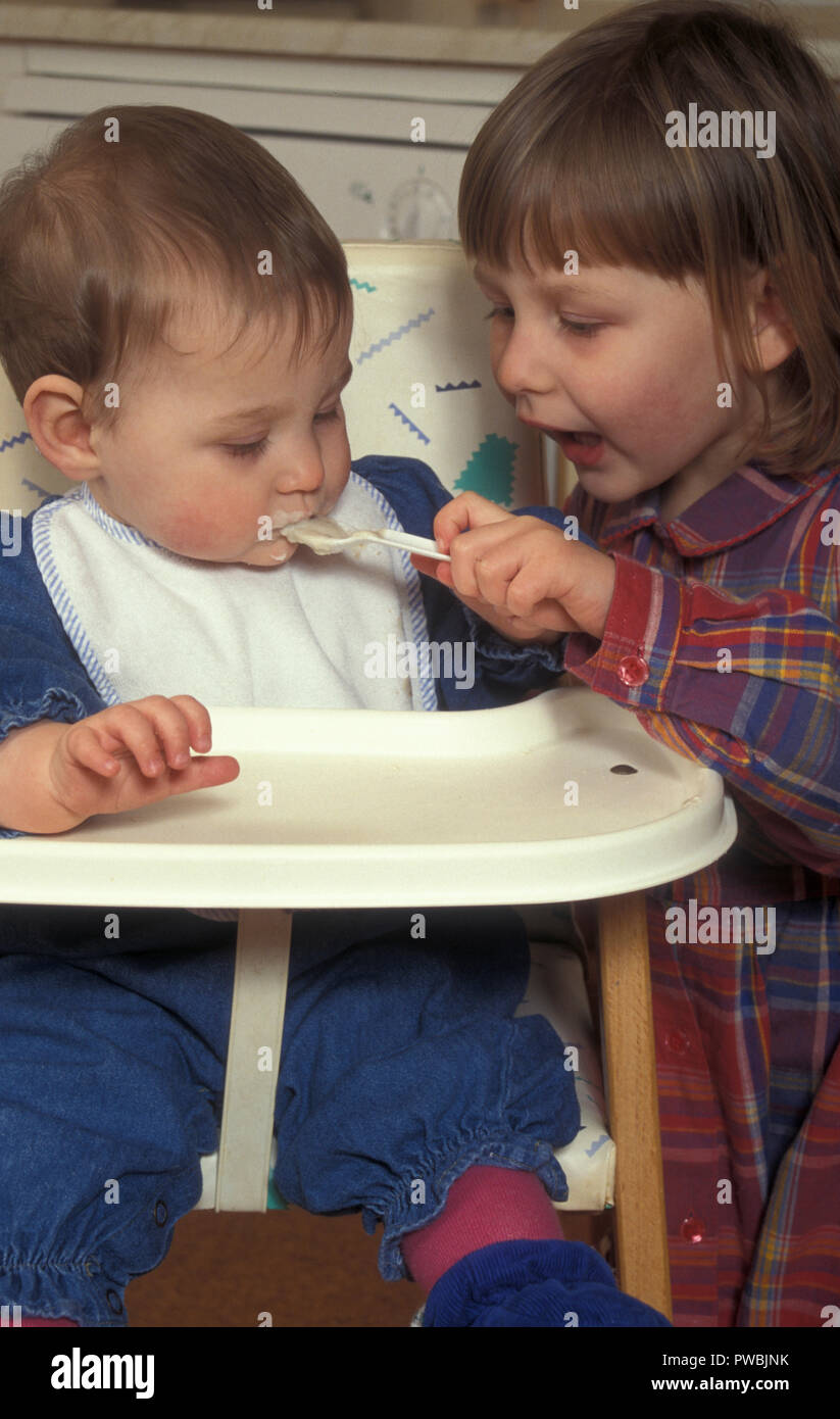 little girl spoonfeeding her baby sister Stock Photo