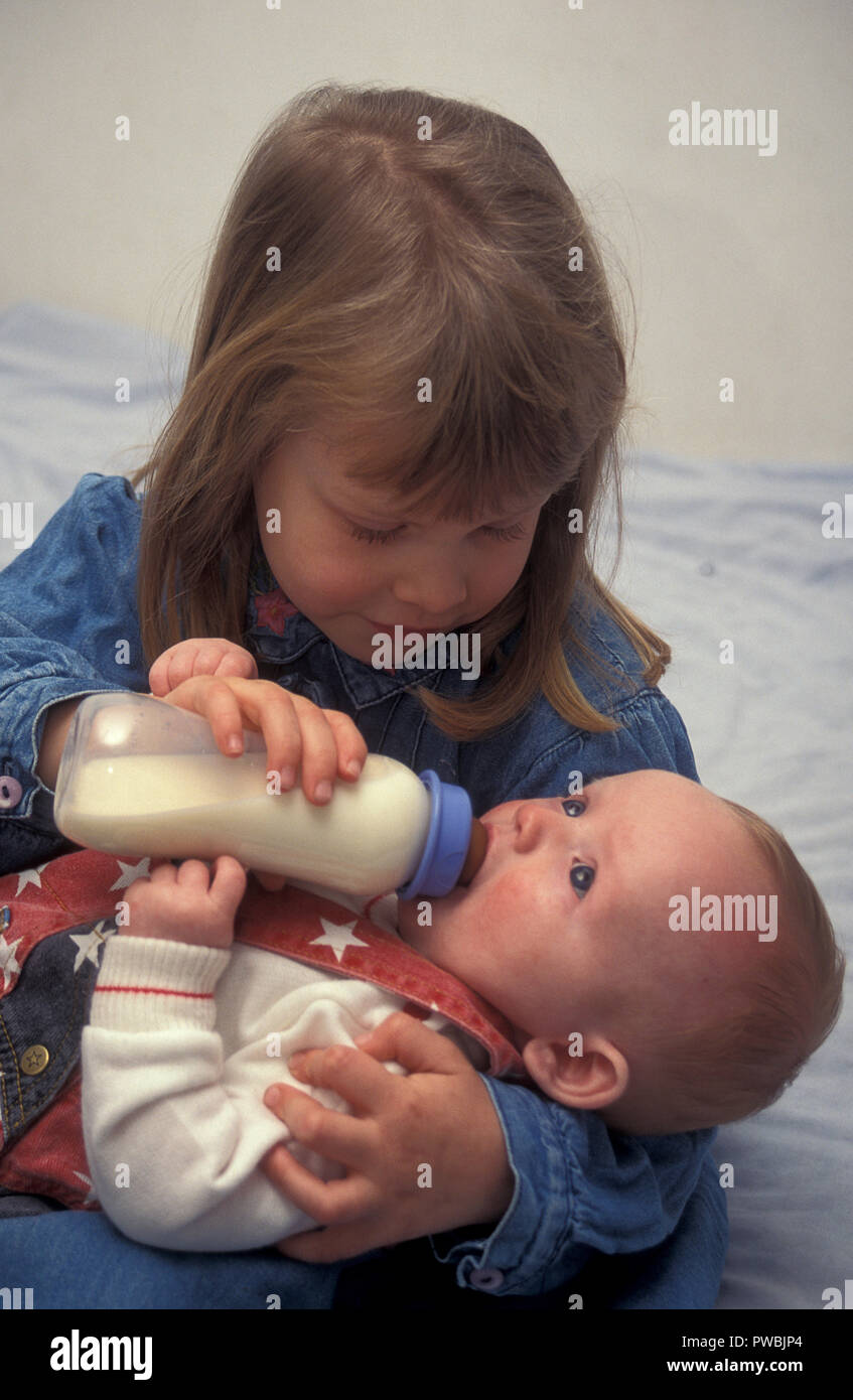 little girl bottlefeeding her baby brother Stock Photo Alamy