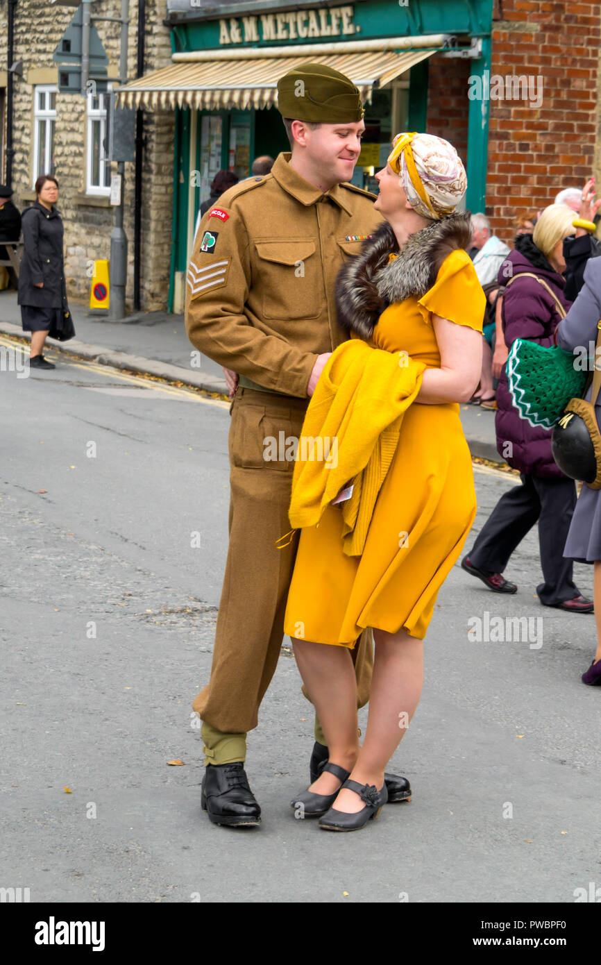 October 2018 a young man dressed as an army embraces a young lady in a yellow dress at an annual re-enactment in Pickering North Yorkshire Stock Photo