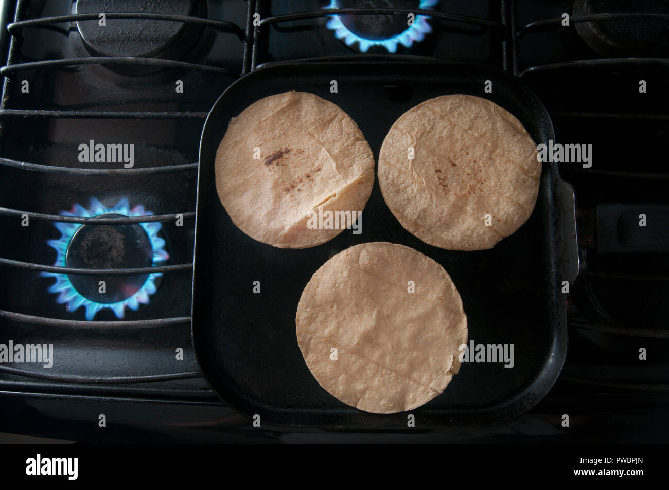 Heating up corn tortilla on top of comal Stock Photo Alamy