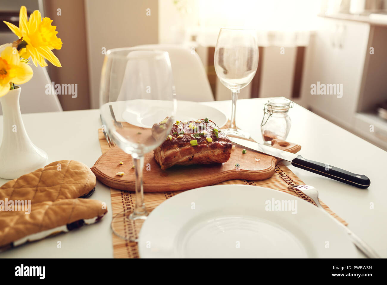 Dinner setting for two served in kitchen. Modern kitchen design. Roasted meat with wine prepared in dining room. Stock Photo